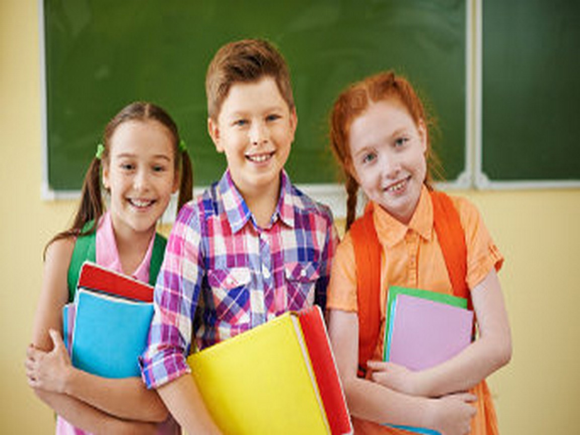 Small group of school friends looking at camera on background of blackboard